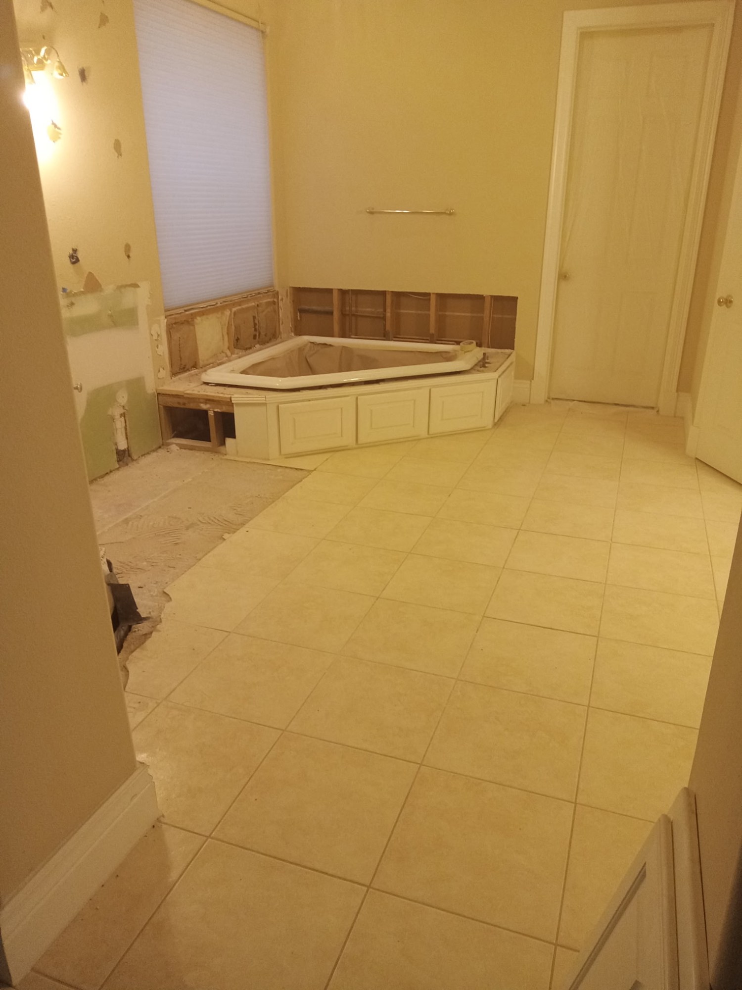 Bathroom renovation before construction with the original corner tub and finishes partially removed