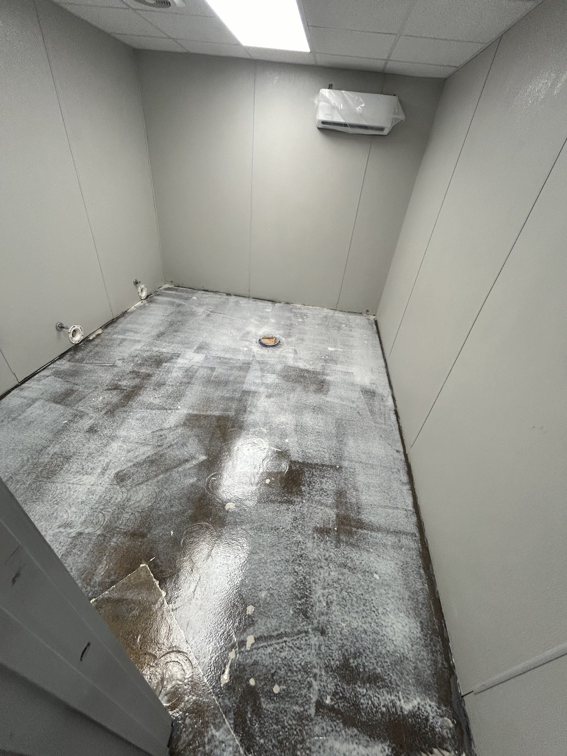 Commercial restroom during improvement work with the floor prepared and fixtures removed