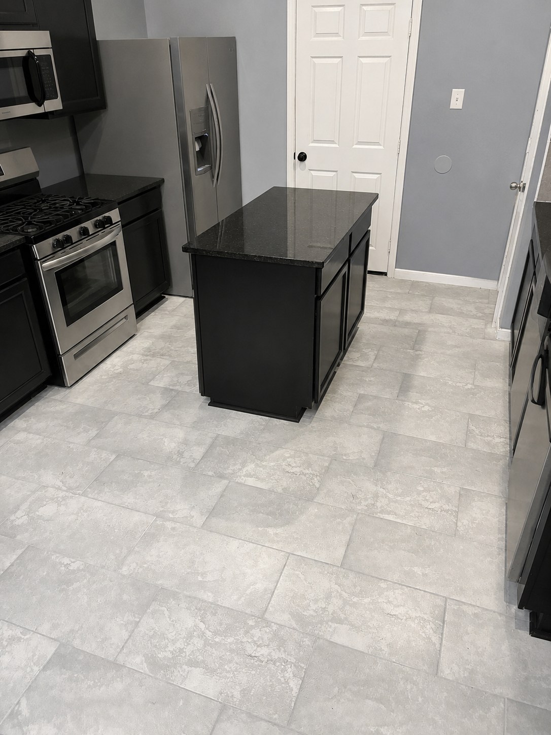 Kitchen after flooring replacement with large-format gray tile and a clean finished installation