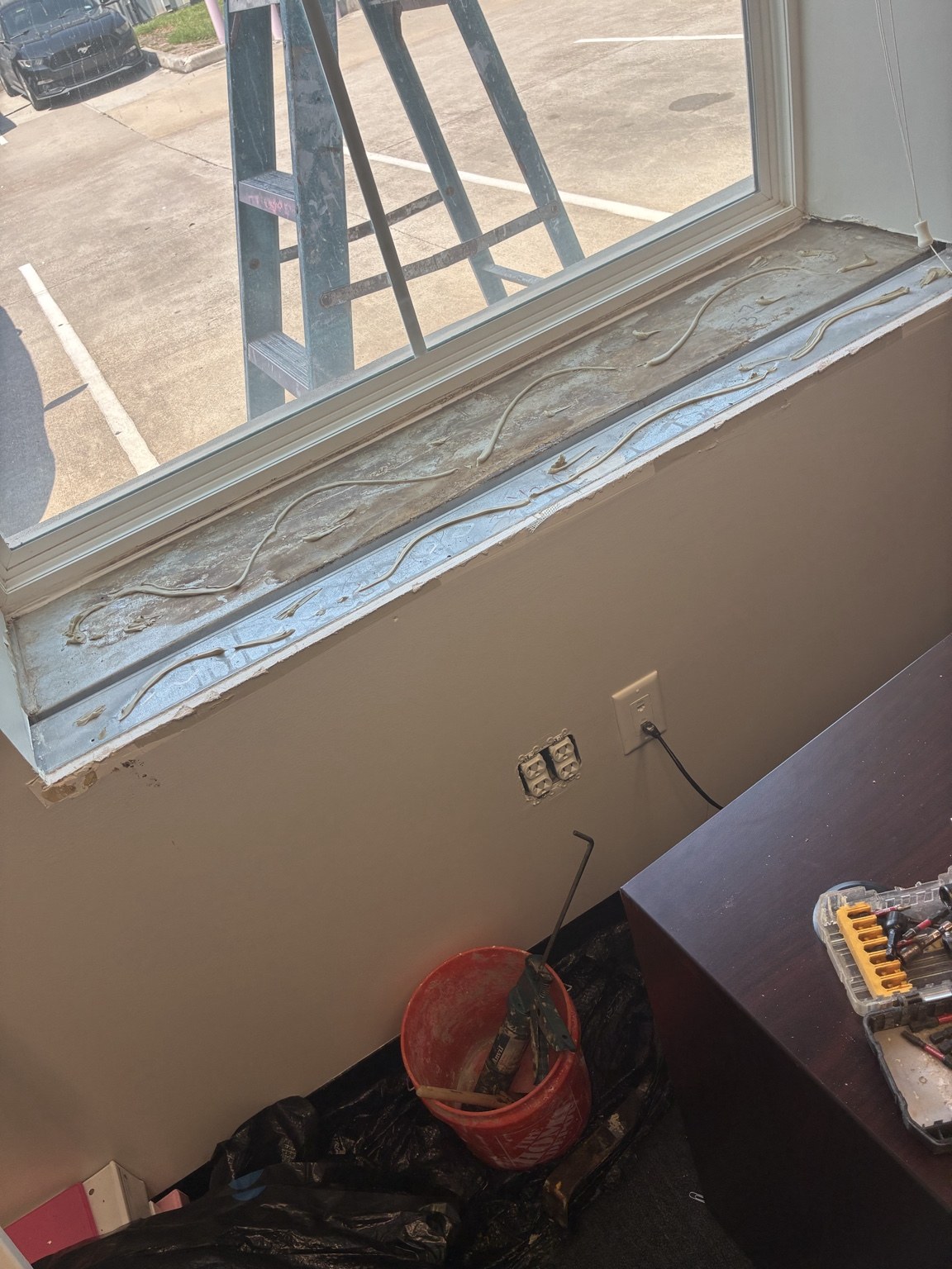 Commercial office window sill before repair with damaged trim and exposed adhesive