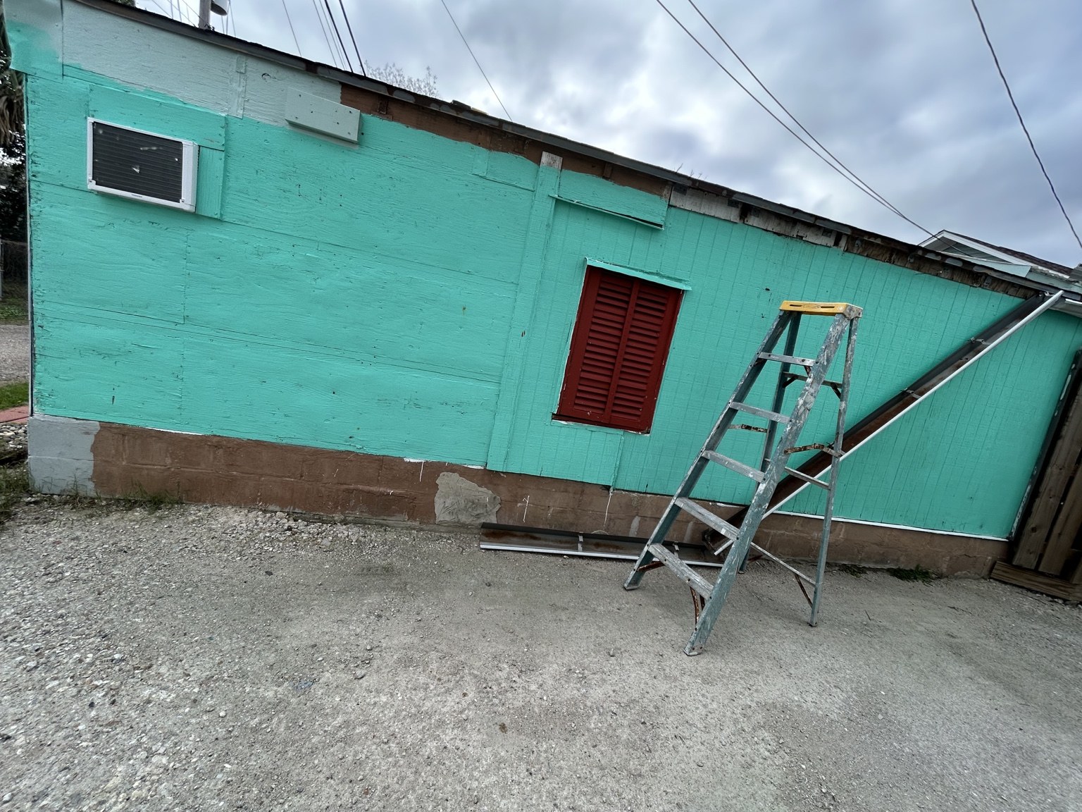 Exterior structure before siding improvement with weathered green wall panels and exposed trim areas