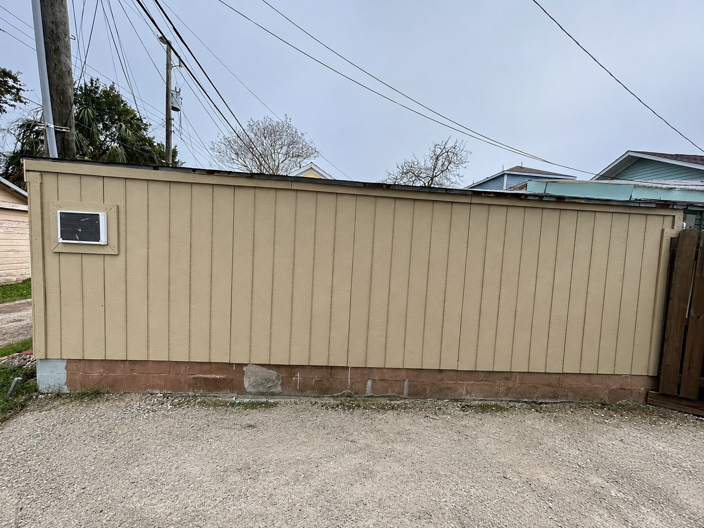 Exterior structure after installation and finishing of tan vertical siding and trim