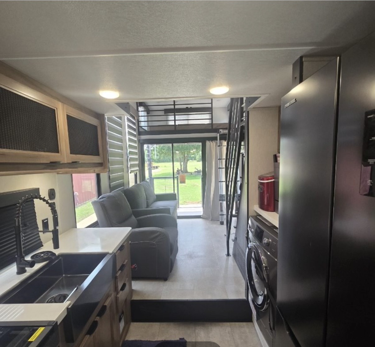 Timberwolf Mini Loft kitchen with full-size refrigerator, washer and dryer, reclining seats, and rear patio view